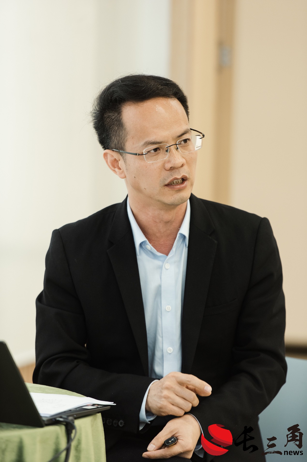 A person in a suit sitting at a deskDescription automatically generated