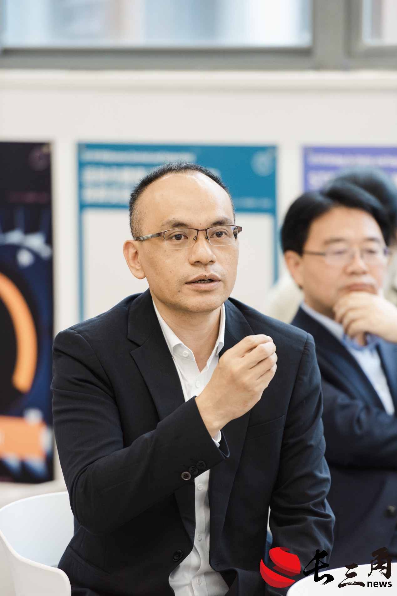 A person in a suit sitting at a tableDescription automatically generated